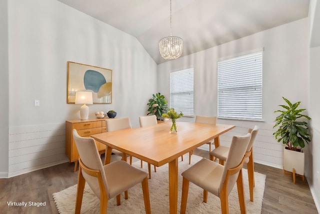 dining area with an inviting chandelier, wood finished floors, and vaulted ceiling