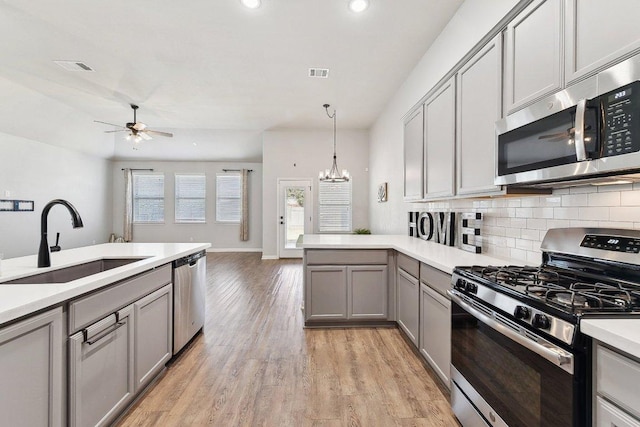 kitchen featuring visible vents, ceiling fan with notable chandelier, gray cabinets, stainless steel appliances, and a sink