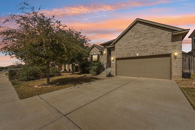 view of front of home featuring concrete driveway, an attached garage, and brick siding