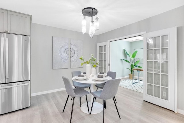 dining room with an inviting chandelier, light wood-type flooring, and baseboards