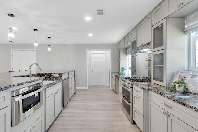 5213 Summerset Trl, Austin, TX 78749 - kitchen featuring stainless steel appliances, under cabinet range hood, recessed lighting, light wood-style flooring, and dark stone countertops