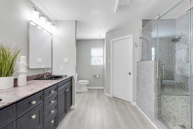 full bath with vanity, wood finished floors, visible vents, a stall shower, and toilet