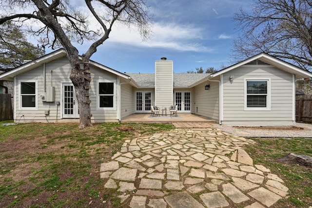 back of property with french doors, a patio area, a chimney, and fence