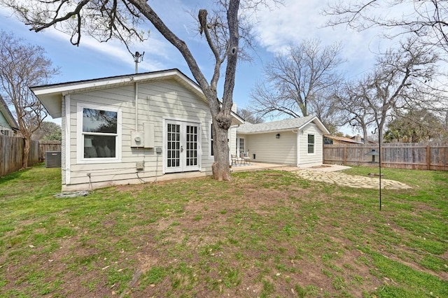 rear view of property featuring a patio, french doors, a lawn, and a fenced backyard