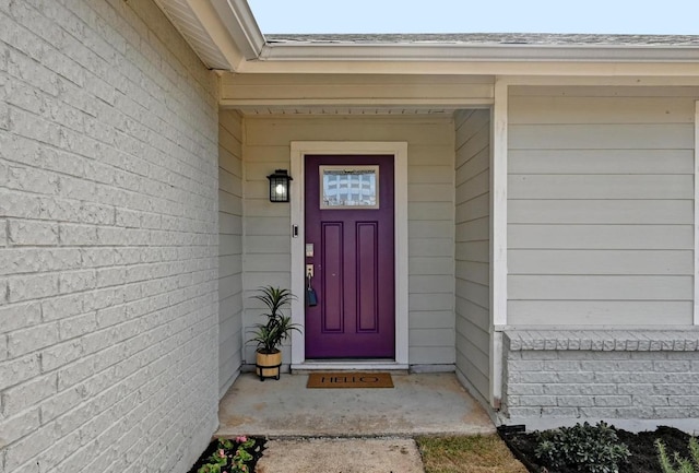 view of exterior entry with roof with shingles