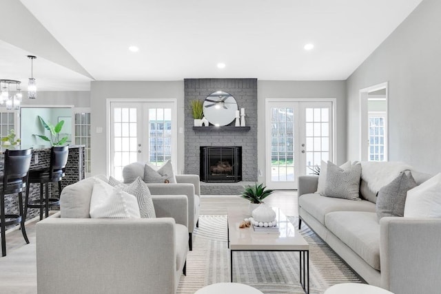 living area featuring french doors, lofted ceiling, and a healthy amount of sunlight