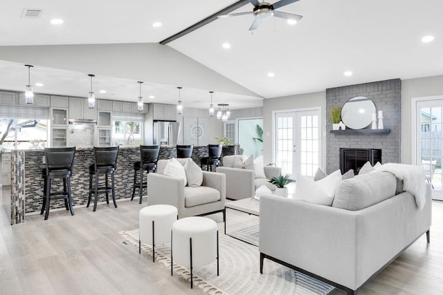 living room with visible vents, a brick fireplace, a ceiling fan, and light wood-style floors