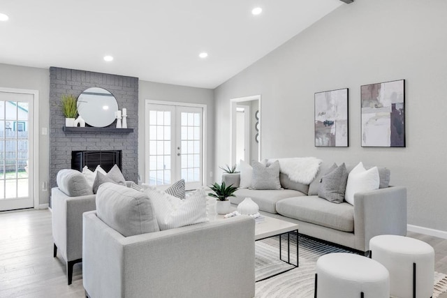 living room featuring plenty of natural light, light wood-type flooring, and vaulted ceiling