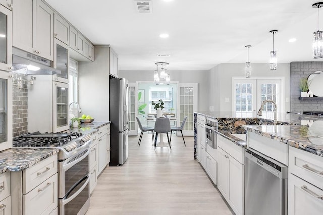 5213 Summerset Trl, Austin, TX 78749 - kitchen with appliances with stainless steel finishes, under cabinet range hood, a chandelier, light wood-type flooring, and french doors