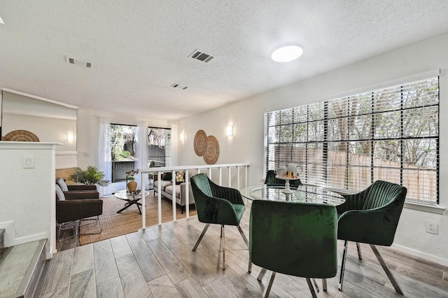 dining area featuring visible vents, a textured ceiling, and wood finished floors