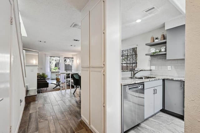 kitchen featuring visible vents, wood finish floors, open shelves, a sink, and dishwasher