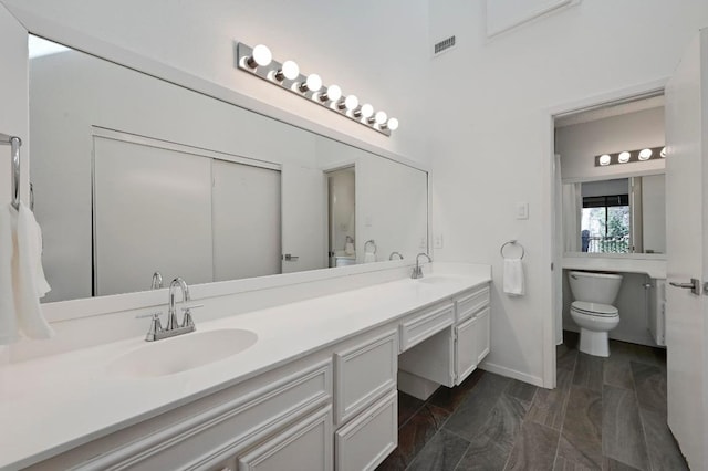 bathroom featuring a sink, visible vents, toilet, and double vanity