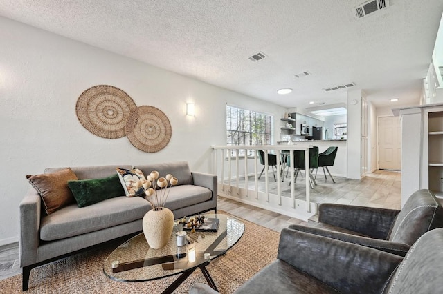 living room with visible vents, a textured ceiling, and wood finished floors