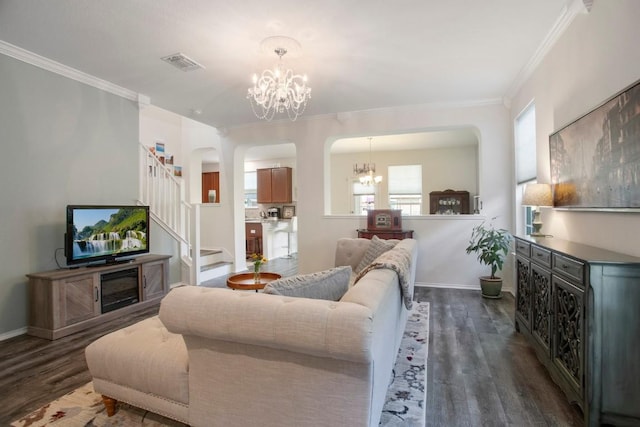 living area with visible vents, a notable chandelier, dark wood-type flooring, arched walkways, and crown molding