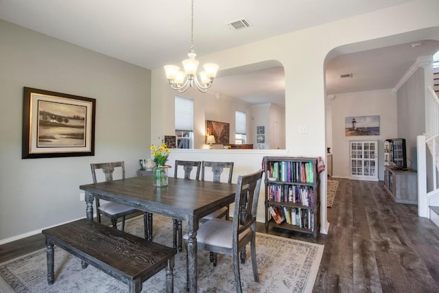 dining area with visible vents, wood finished floors, arched walkways, baseboards, and a chandelier