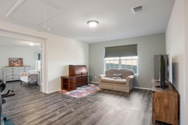 living room with visible vents, baseboards, attic access, and dark wood finished floors