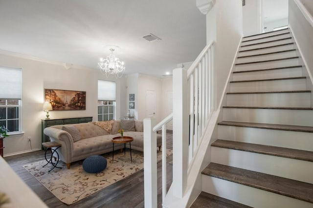 staircase featuring wood finished floors, baseboards, visible vents, crown molding, and a chandelier