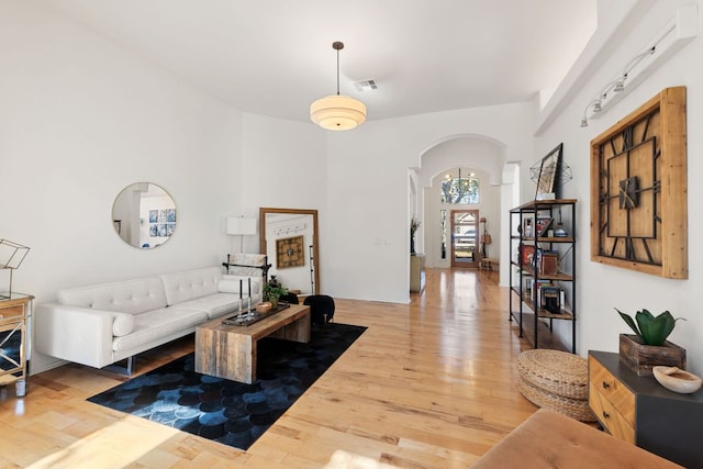 living area with visible vents, arched walkways, and wood finished floors