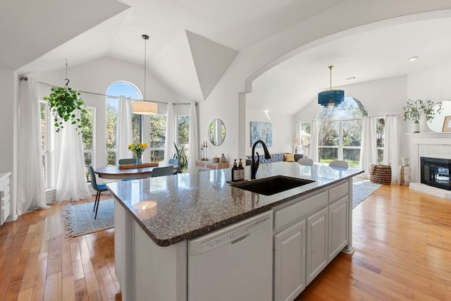 kitchen featuring open floor plan, white dishwasher, light wood finished floors, and a sink