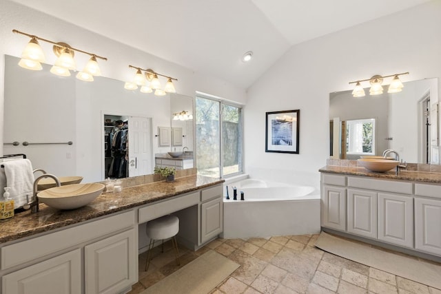 bathroom with vaulted ceiling, a healthy amount of sunlight, and a sink