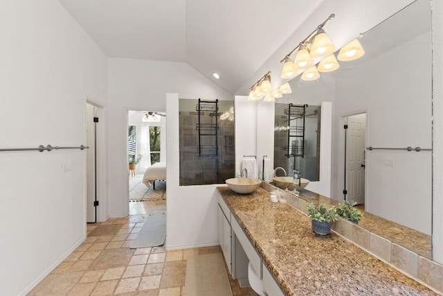 ensuite bathroom with ensuite bathroom, stone tile flooring, baseboards, vanity, and vaulted ceiling