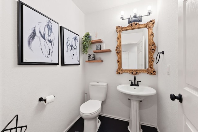 half bathroom featuring toilet and baseboards