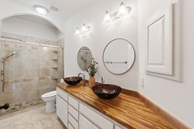 full bathroom with double vanity, a stall shower, visible vents, and a sink