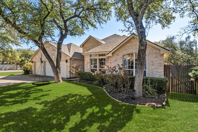 view of front of house featuring a front yard, brick siding, an attached garage, and fence