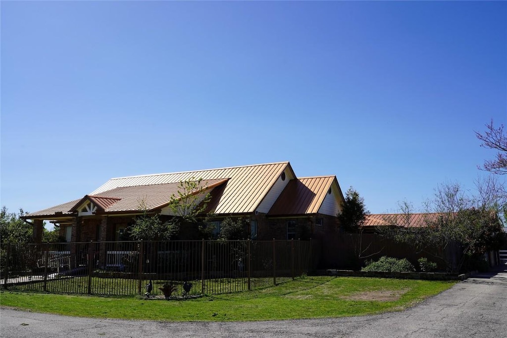 exterior space featuring a fenced front yard, a standing seam roof, metal roof, and a yard