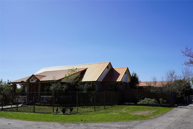 exterior space featuring a fenced front yard, a standing seam roof, metal roof, and a yard