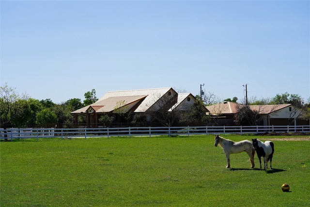 view of yard with an enclosed area, a rural view, and fence