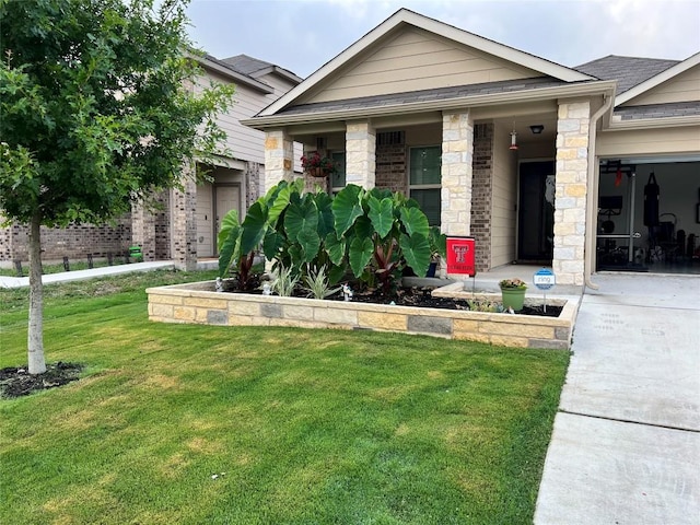 view of front of house with a front lawn, concrete driveway, and stone siding