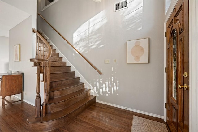 staircase with visible vents, baseboards, and wood finished floors