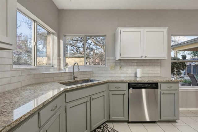 kitchen with a sink, tasteful backsplash, stainless steel dishwasher, and light stone countertops