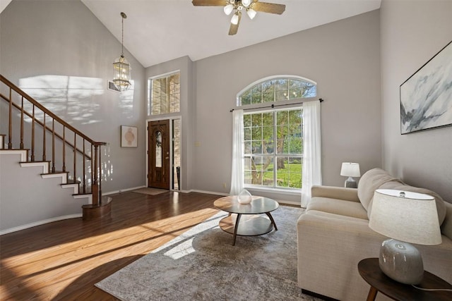 living room featuring high vaulted ceiling, wood finished floors, stairway, baseboards, and ceiling fan