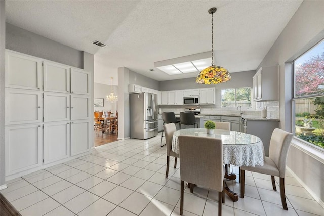 dining room with an inviting chandelier, light tile patterned floors, baseboards, and visible vents