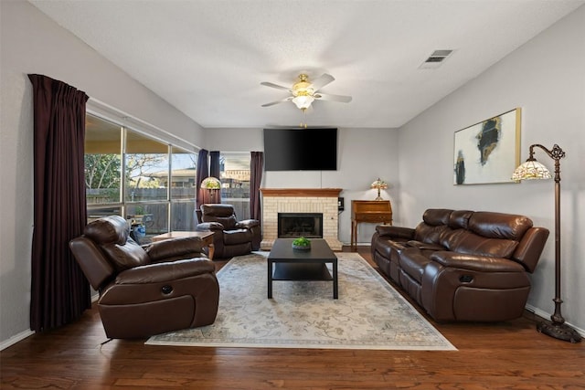 living area featuring wood finished floors, a ceiling fan, visible vents, and baseboards