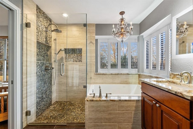 full bathroom with a notable chandelier, a stall shower, vanity, and a bath