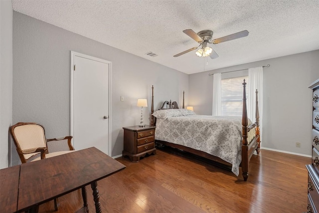 bedroom featuring a textured ceiling, wood finished floors, visible vents, and baseboards