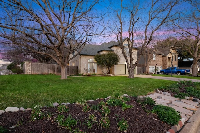 view of yard featuring an attached garage, concrete driveway, and fence