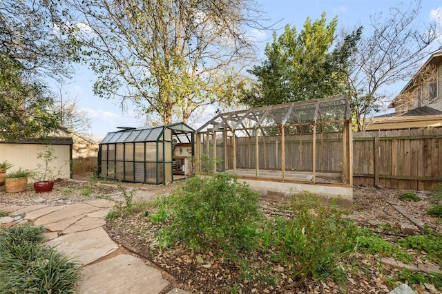 view of yard featuring a greenhouse, an outbuilding, and fence