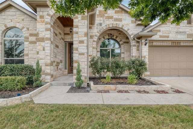 property entrance with stone siding, an attached garage, and driveway