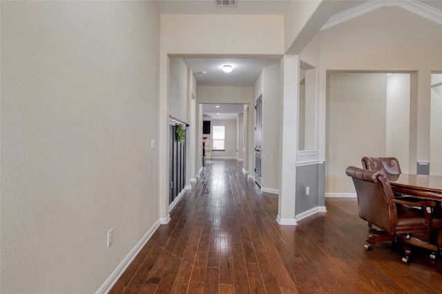 corridor with visible vents, baseboards, and dark wood-style floors