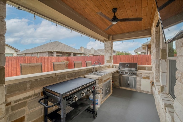 view of patio / terrace with a fenced backyard, a sink, exterior kitchen, and a grill