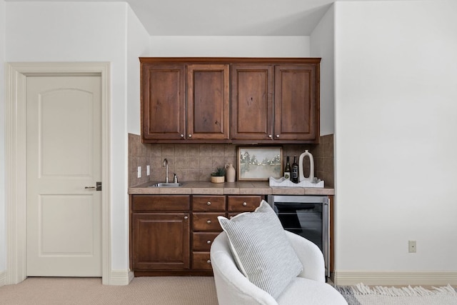 kitchen with wine cooler, tasteful backsplash, light countertops, and a sink