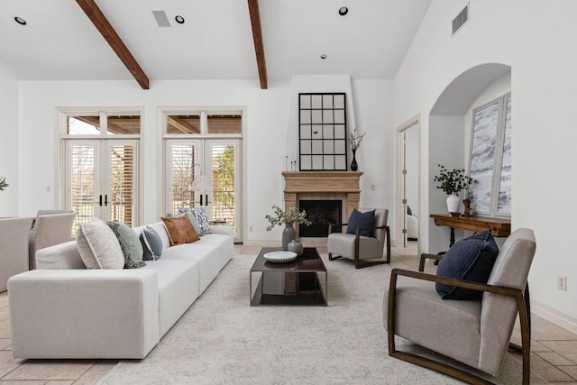 living room with visible vents, beam ceiling, french doors, a fireplace, and a high ceiling