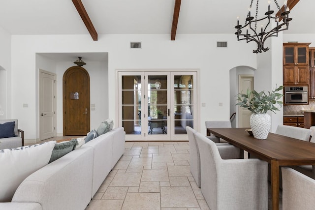 living room with visible vents, stone tile flooring, french doors, arched walkways, and a notable chandelier