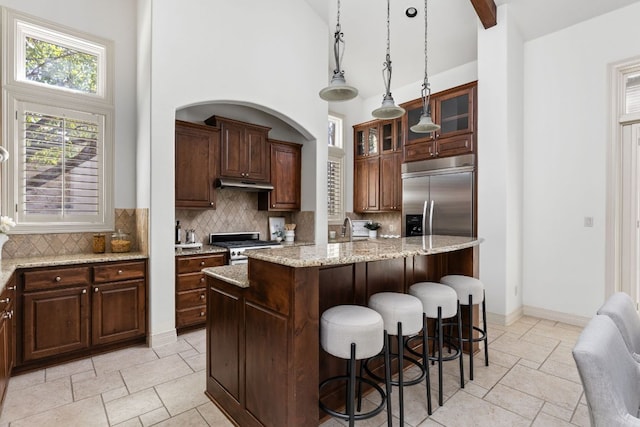 9100 Calera Dr Unit 10, Austin, TX 78735 - kitchen with appliances with stainless steel finishes, under cabinet range hood, high vaulted ceiling, tasteful backsplash, and a kitchen breakfast bar