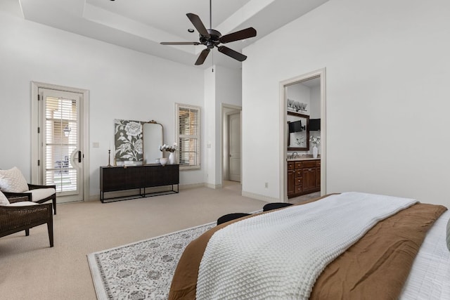 bedroom with access to exterior, baseboards, a tray ceiling, light carpet, and a towering ceiling