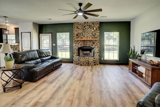 living area with a fireplace, visible vents, light wood finished floors, and ceiling fan